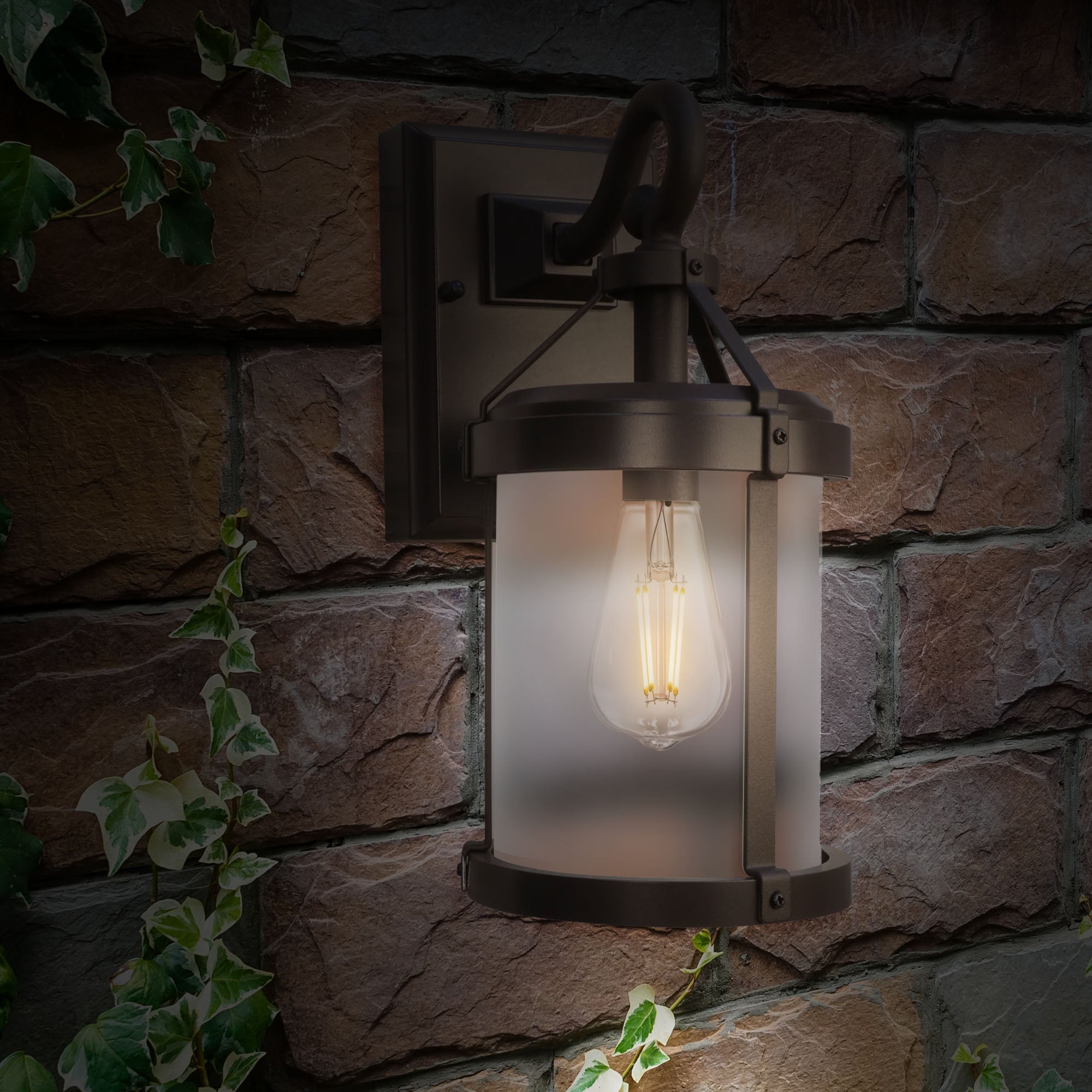 Outdoor wall light fixture on a stone wall with a warm glow.