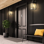 Modern entranceway with wall lights, a black door, bench, and potted plant.